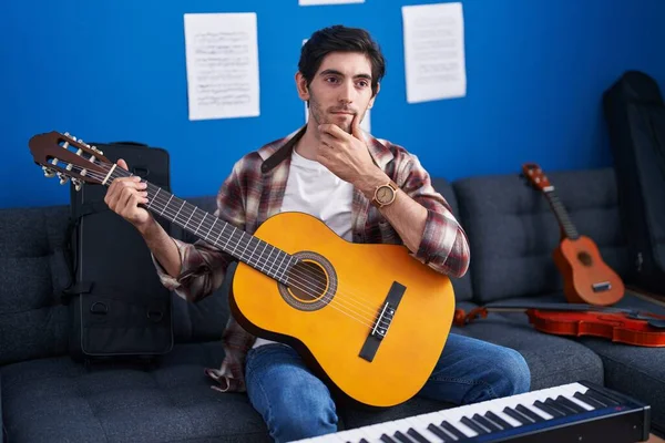若いヒスパニック男演奏クラシックギターで音楽スタジオ深刻な顔を考えて質問について手であご 混乱のアイデアについて思慮深い — ストック写真