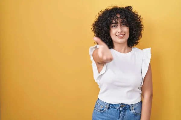 年轻的中东女人站在黄色的背景上 友好地微笑 握手致意和欢迎 成功的商业 — 图库照片