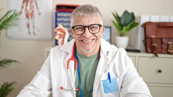 Grauhaariger Arzt Mittleren Alters Sitzt Auf Tisch Und Lächelt Klinik — Stockfoto