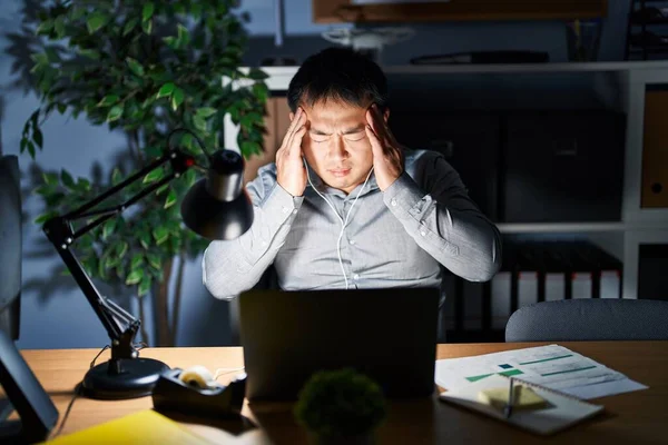 ストレスが原因で頭の痛みのために頭の上に手で夜にコンピュータのラップトップを使用して作業している若い中国人男性 片頭痛 — ストック写真