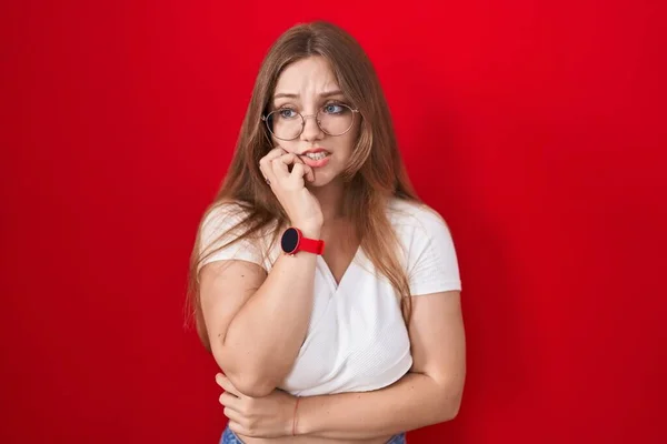 Młoda Biała Kobieta Stojąca Nad Czerwonym Tłem Wyglądająca Zestresowaną Zdenerwowaną — Zdjęcie stockowe
