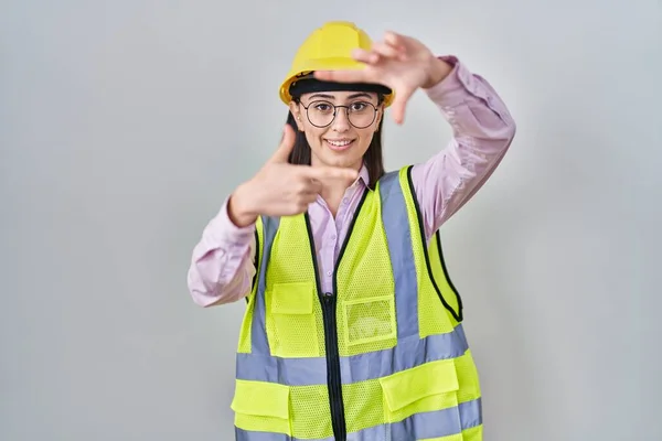 身穿建筑工人制服 头戴硬礼帽的西班牙裔女孩笑容满面 手指手画脚 创意与摄影概念 — 图库照片