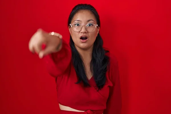 Asyalı Genç Bir Kadın Kırmızı Arka Planda Dikiliyor Parmağıyla Işaret — Stok fotoğraf