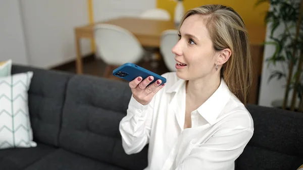 Young Blonde Woman Sending Voice Message Smartphone Sitting Sofa Home — Fotografia de Stock