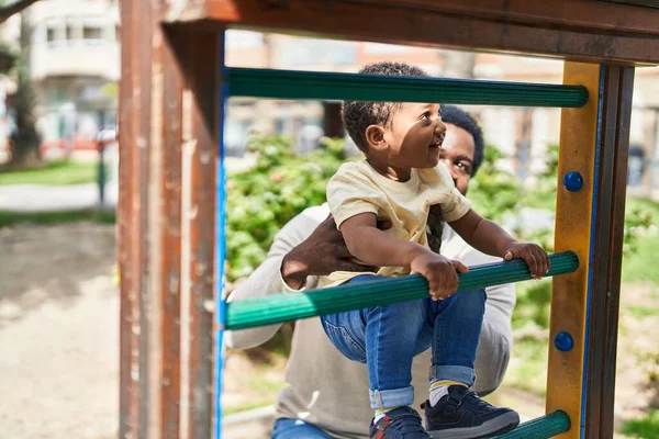 Baba ve oğul oyun alanında kaydırak oynuyorlar.