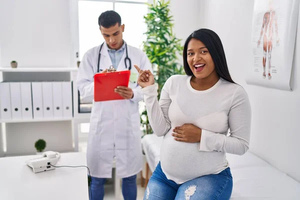 年轻的他惊慌失措的母亲期待着一个婴儿出现在医生面前 高兴地微笑着 手指头指向旁边 — 图库照片