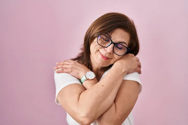 Middle Age Hispanic Woman Standing Pink Background Hugging Oneself Happy — Stockfoto