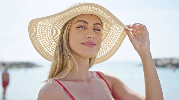 年轻的金发女游客带着自信的笑容 戴着比基尼和夏帽在海滩上游览 — 图库照片
