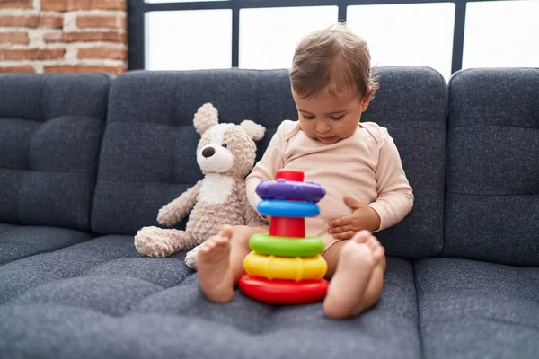 愛らしいHispanic赤ちゃん遊びとともにフープゲーム座っていますソファに家 — ストック写真