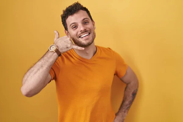 Sarı Arka Planda Durup Gülümseyen Parmaklarıyla Telefonla Konuşan Spanyol Bir — Stok fotoğraf