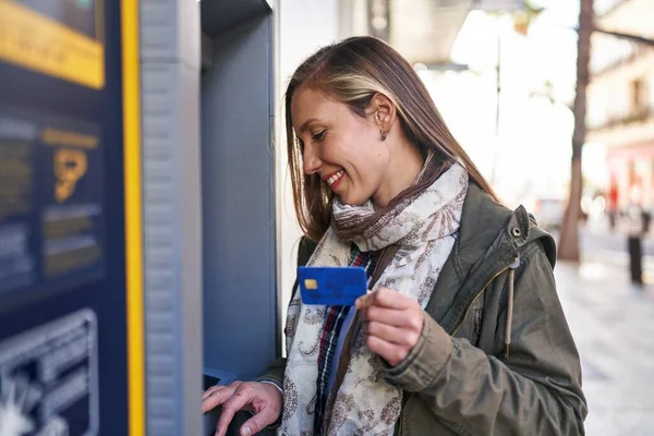年轻的金发女人带着自信的笑容在银行出纳员面前拿着信用卡 — 图库照片