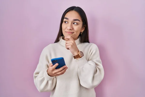 Młoda Południowoazjatycka Kobieta Pomocą Smartfona Poważna Twarz Myśląc Pytaniu Ręki — Zdjęcie stockowe