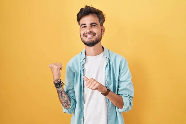 Mladý Hispánec Tetováním Stojící Nad Žlutým Pozadím Ukazující Zadní Stranu — Stock fotografie