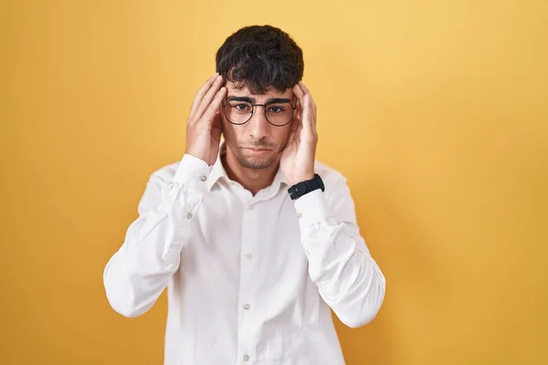 若いヒスパニック系の男の頭の上に手で黄色の背景に立って 頭痛の種のため ストレス 片頭痛 — ストック写真