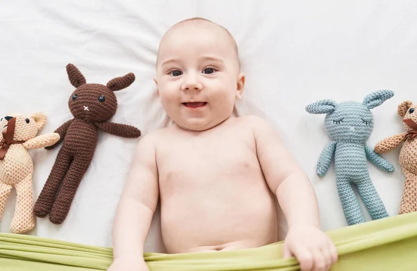 Sevimli Beyaz Bebek Yatakta Oyuncak Bebeklerle Gülümsüyor — Stok fotoğraf