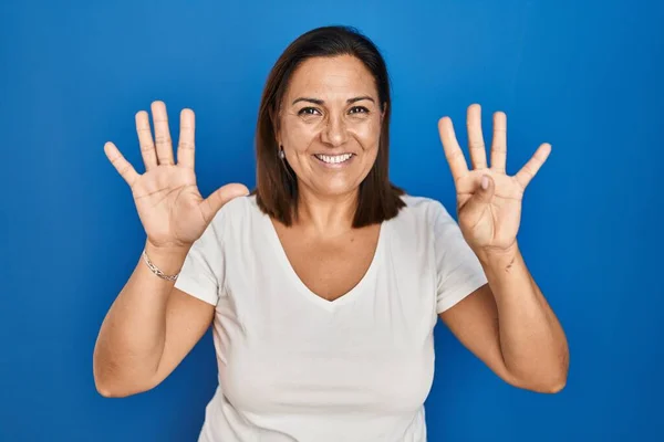 西班牙裔成熟女人站在蓝色的背景上 用9号手指指指指点点 面带微笑 自信而快乐 — 图库照片