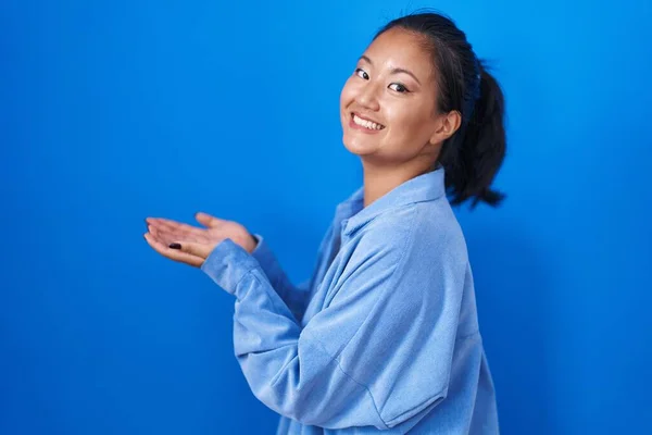 Aziatisch Jong Vrouw Staande Blauwe Achtergrond Wijzen Opzij Met Handen — Stockfoto