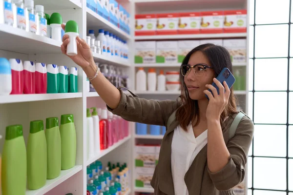 年轻的亚洲女性顾客在药店拿着除臭剂在讲智能手机 — 图库照片
