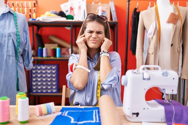 西班牙裔年轻女性服装设计师在工作室里用手指捂住耳朵 对嘈杂的音乐感到恼怒 聋人概念 — 图库照片