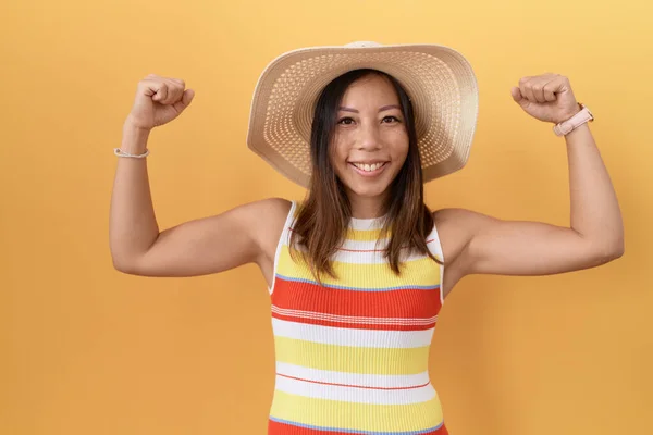 中年妇女头戴夏帽 身披黄底 露出臂膀肌肉微笑 感到自豪 健身概念 — 图库照片