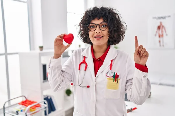Hispanic Doctor Woman Curly Hair Holding Heart Surprised Idea Question — Stock Photo, Image