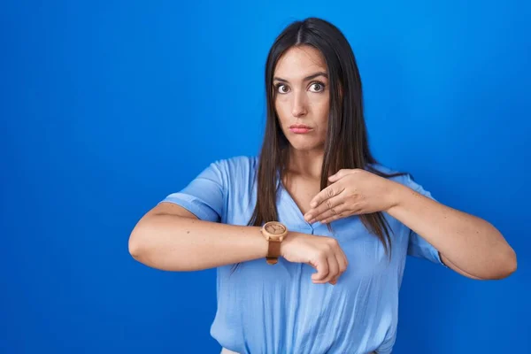 Young Brunette Woman Standing Blue Background Hurry Pointing Watch Time — Stock Photo, Image