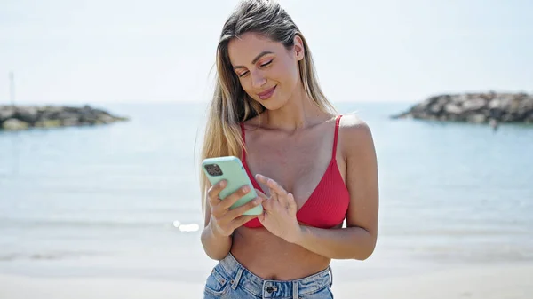 해변에서 스마트폰을 사용하여 비키니를 금발의 — 스톡 사진
