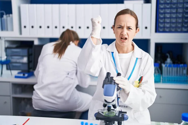 Blonde woman working on cruelty free laboratory annoyed and frustrated shouting with anger, yelling crazy with anger and hand raised
