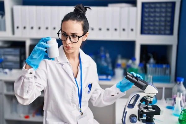 Young Caucasian Woman Scientist Using Microscope Holding Pills Bottle Laboratory — ストック写真