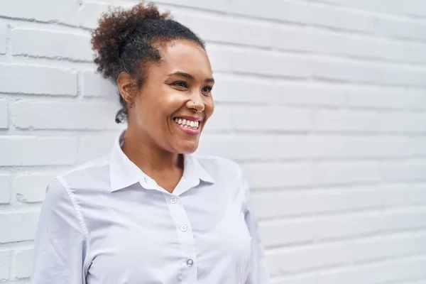 Африканська Американка Усміхається Впевнено Дивлячись Збоку Ізольований Білий Цегляний Фон — стокове фото