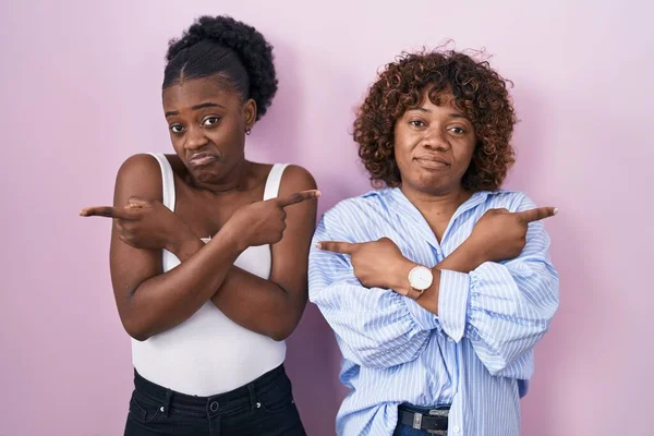 Две Африканки Стоящие Розовом Фоне Указывая Пальцами Обе Стороны Разных — стоковое фото