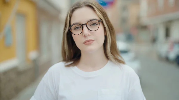 年轻的高加索女人戴着眼镜站在街上严肃地看着 — 图库照片