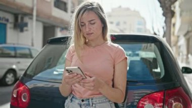 Sokakta duran akıllı telefonu kullanan genç sarışın kadın.