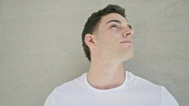 Soyutlanmış beyaz arka planda ciddi bir ifadeyle yan tarafa bakan İspanyol genç adam.