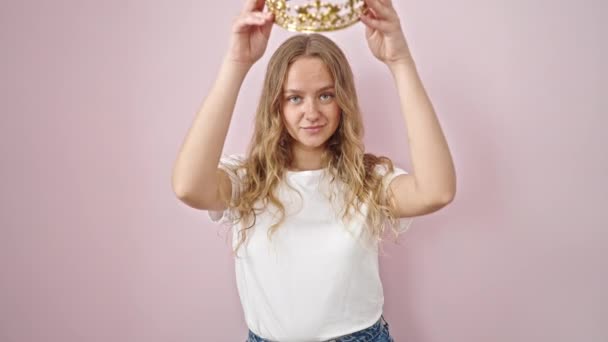 Młoda Blondynka Uśmiecha Się Pewnie Nosząc Koronę Księżniczki Odizolowanym Różowym — Wideo stockowe