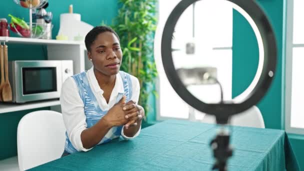 アフリカ系アメリカ人女性がダイニングルームでソーシャルネットワークのためのオンラインチュートリアルを記録 — ストック動画