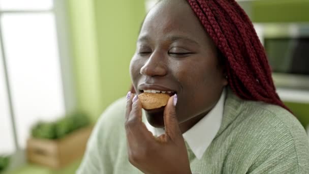 Örgülü Saçlı Afrikalı Kadın Yemek Salonunda Gözleri Kapalı Kurabiye Yiyor — Stok video