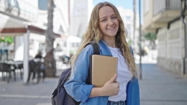 Νεαρή Ξανθιά Φοιτήτρια Χαμογελά Αυτοπεποίθηση Κρατώντας Βιβλία Στο Δρόμο — Αρχείο Βίντεο