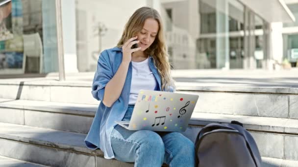 在大学里 年轻的金发女学生用笔记本电脑用智能手机聊天 — 图库视频影像