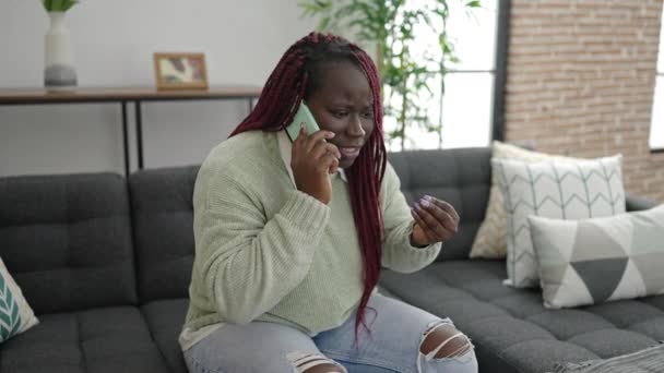 自宅で心配そうな表情で電話で話して編組の髪を持つアフリカの女性 — ストック動画