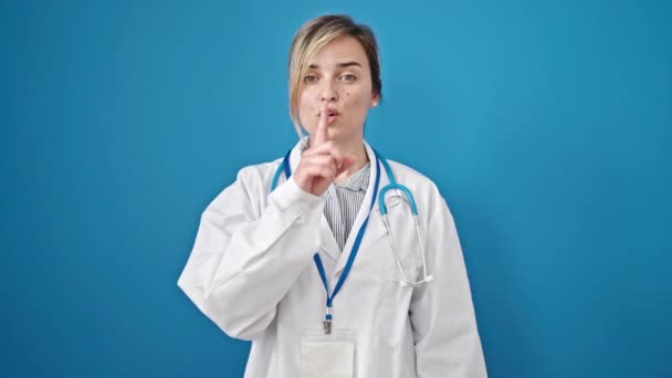 年轻的金发碧眼的女医生要求对孤立的蓝色背景保持沉默 — 图库视频影像