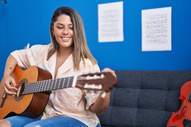 Genç İspanyol kadın müzisyen müzik stüdyosunda klasik gitar çalıyor.