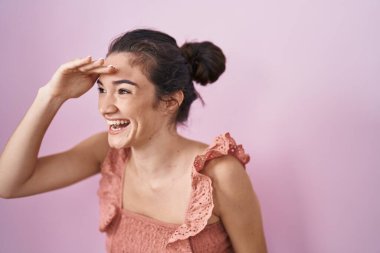 Pembe arka planda duran genç kız çok mutlu ve gülümsüyor. Çok uzaklara bakıyor. arama kavramı. 
