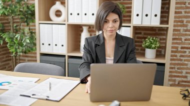 Ofiste çalışan genç beyaz kadın iş adamı dizüstü bilgisayar kullanıyor.