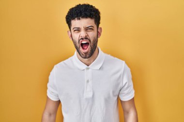 Arap adam sarı arka planda öfkeli ve öfkeli bir şekilde öfkeli sinirli sinirli bağırıyor, öfkeyle bağırıyor. öfke ve agresif konsept. 