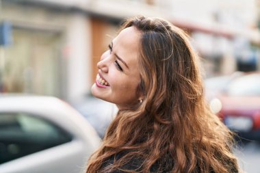 Young beautiful hispanic woman smiling confident looking to the side at street