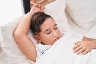 Adorable hispanic boy lying on bed sleeping at bedroom