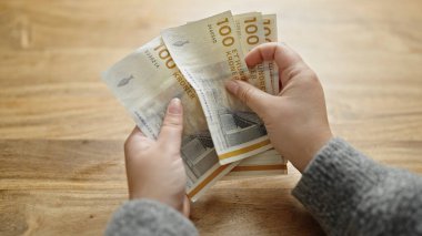 Kadının elleri odada 100 Danimarka kronu sayıyor.