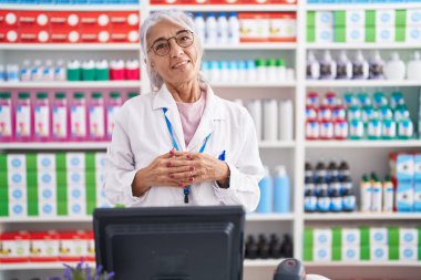 Eczanede çalışan dövmeli orta yaşlı bir kadın ellerini birleştirip gülümseyerek gevşemiş ve neşeliydi. Başarı ve iyimserlik 