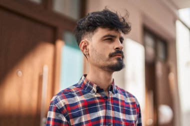 Young hispanic man looking to the side with relaxed expression at street